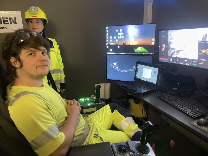 Två arbetare i varselkläder sköter och övervakar utrustningen från ett kontrollrum med flera datorskärmar och kontrollanordningar.
