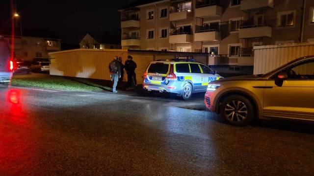 Poliser som står nära en patrullbil i ett bostadsområde på natten, med en annan bil parkerad i närheten.
