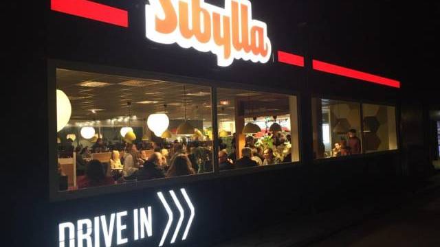 Nattvy av en Sibylla snabbmatsrestaurang med människor som äter inne och en