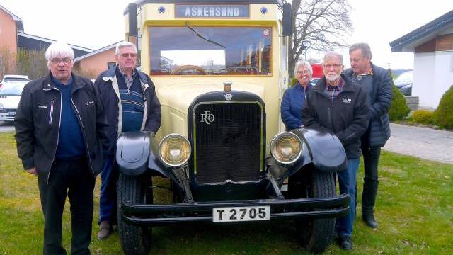 Fem äldre personer står stolta framför en vintagegul buss med destinationsskylten 