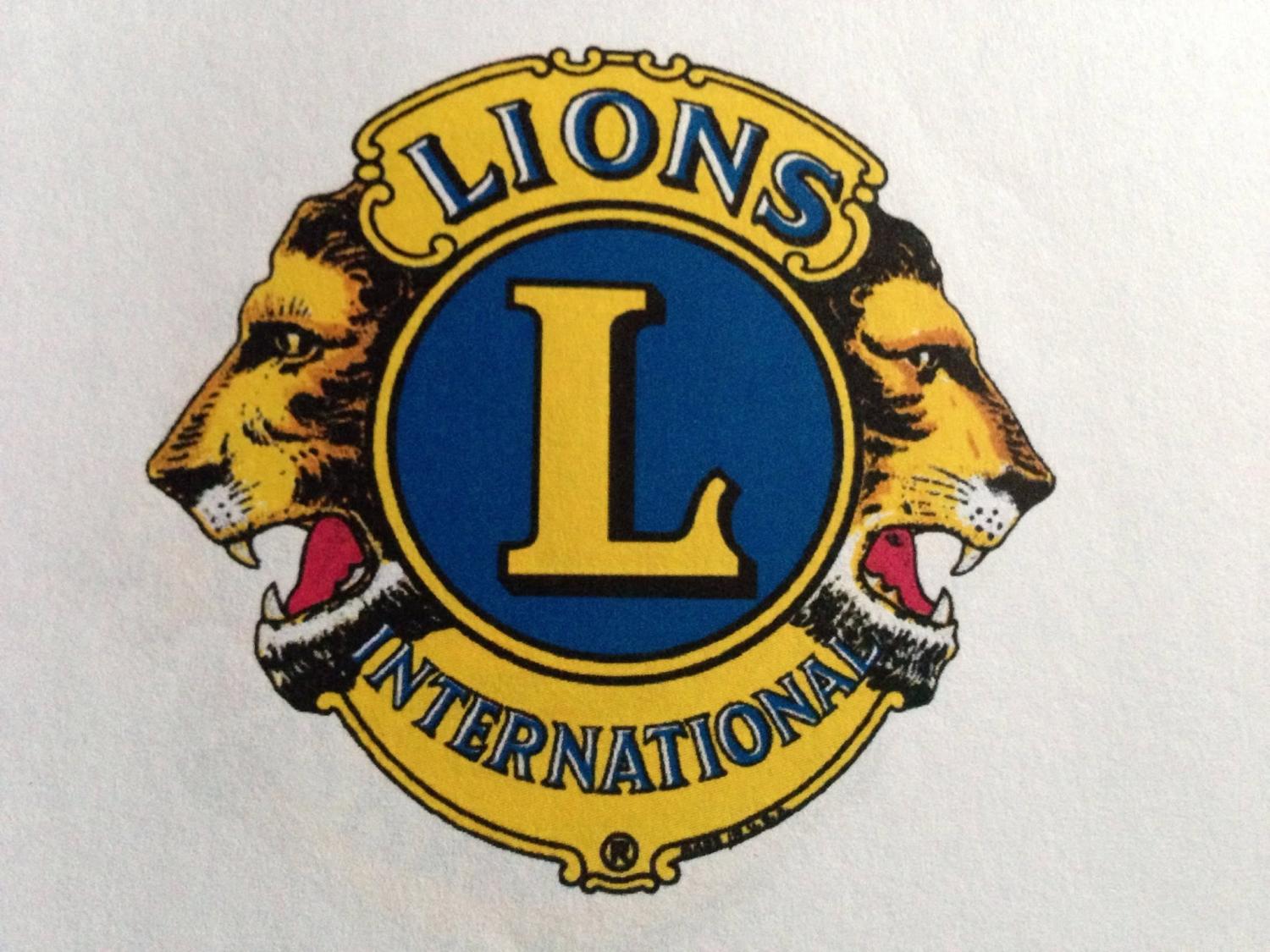Lions Clubs Internationals logotyp, som visar ett stort blått ”L” i mitten med två lejonhuvuden som blickar åt motsatta håll och orden ”Lions” och ”International” runt omkring.