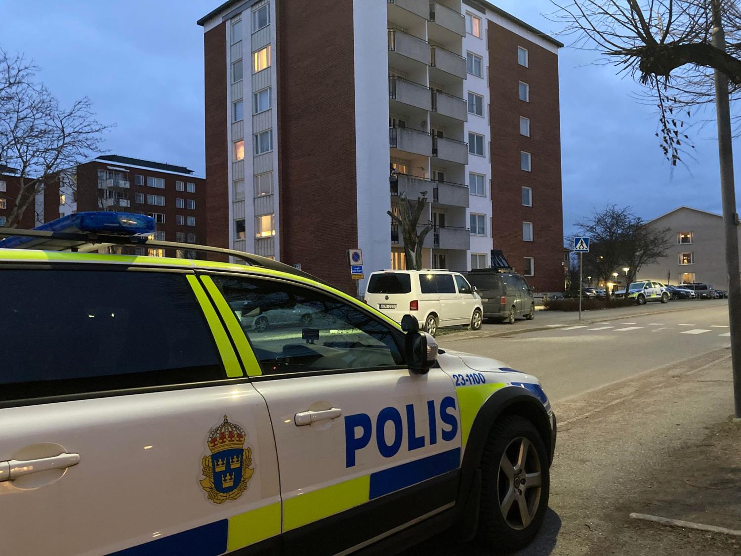 En polisbil står parkerad framför en byggnad.