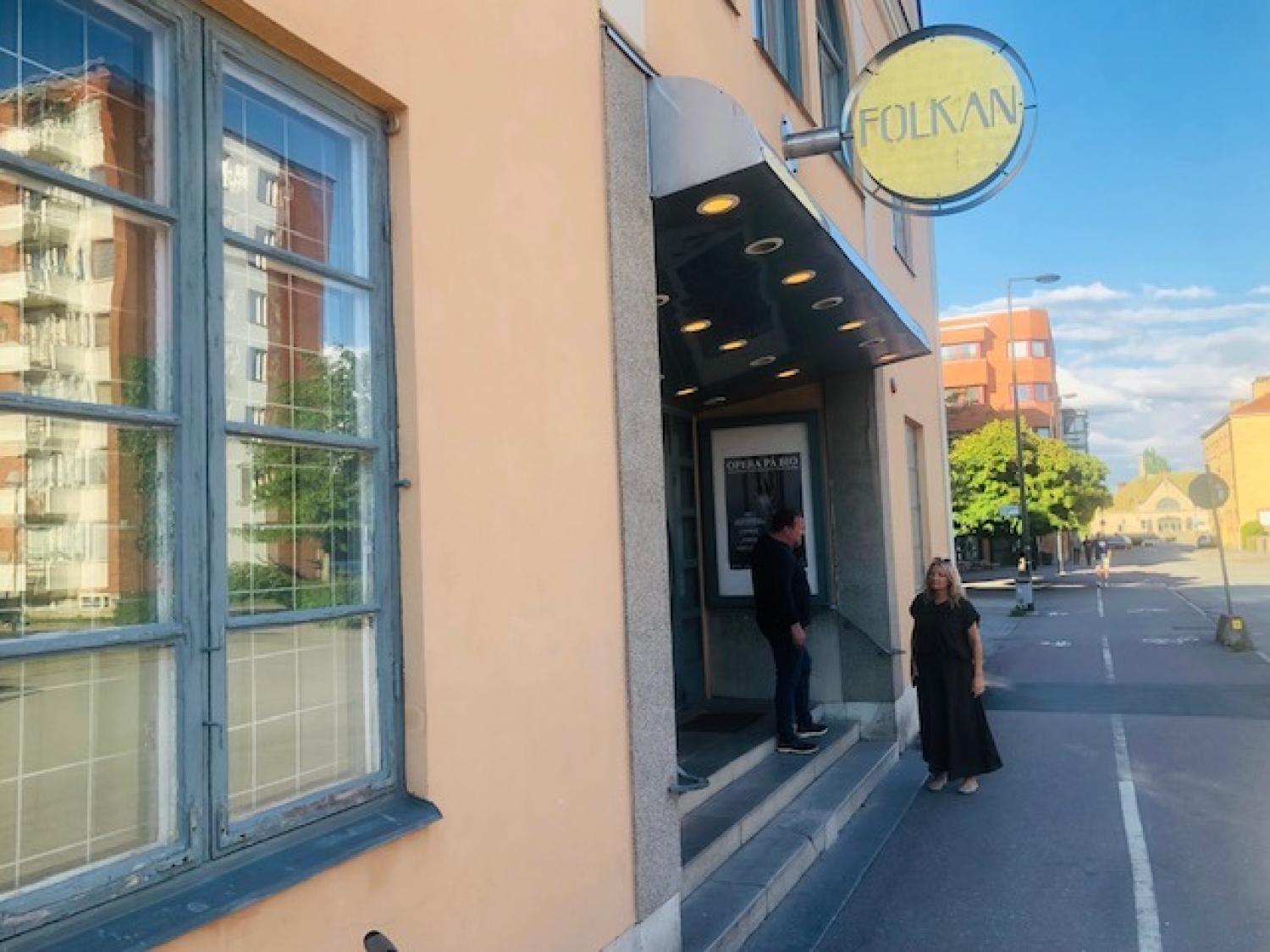 En man och en kvinna står utanför entrén till en byggnad med en
