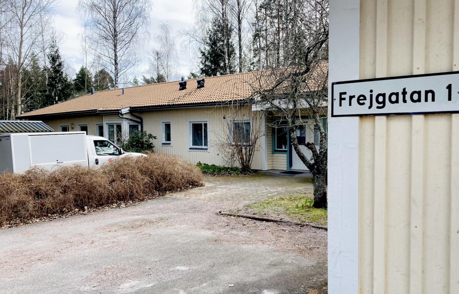 Ett enplanshus med beige fasad, omgivet av kala buskar, beläget på