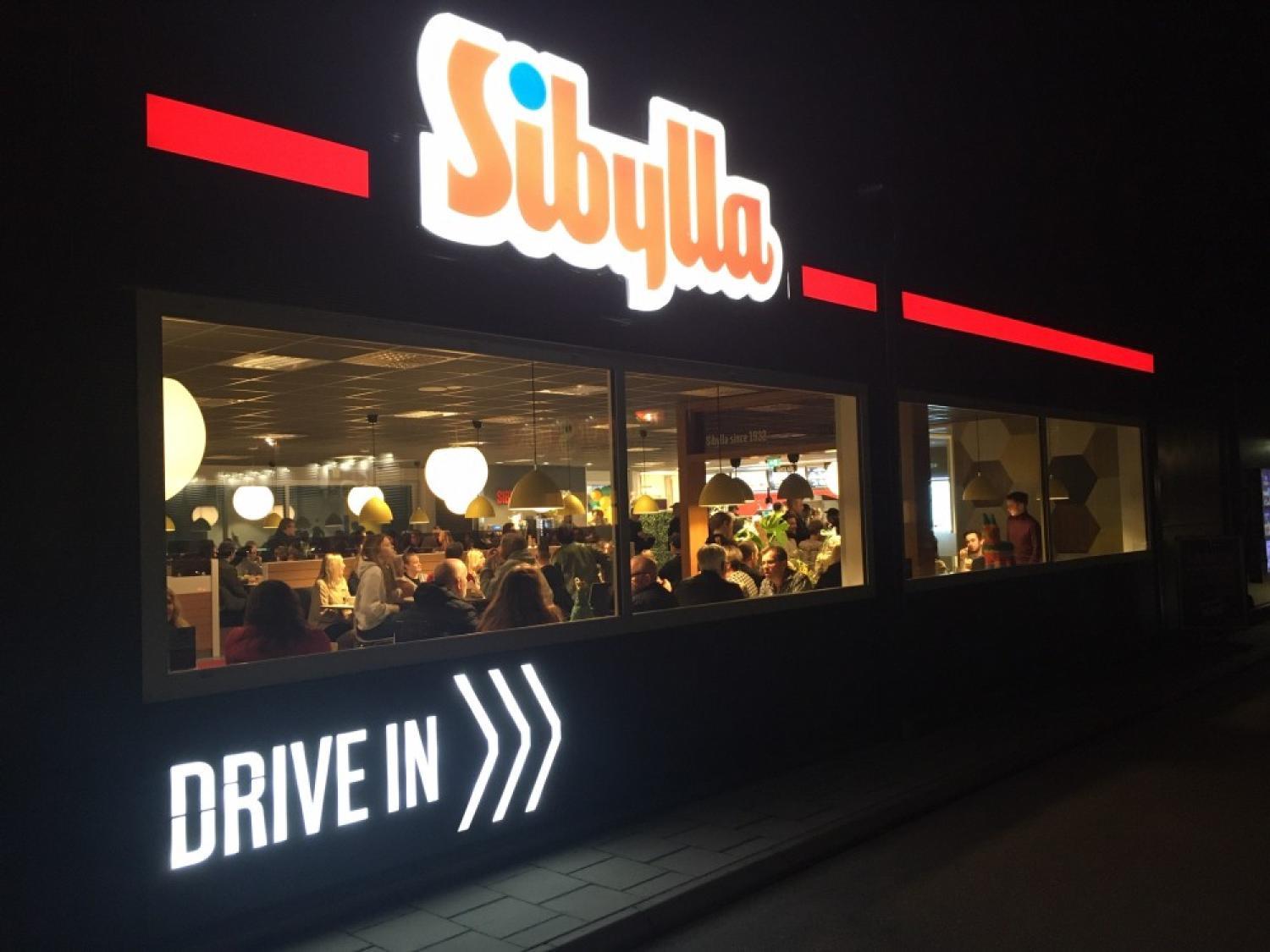 Nattvy av en Sibylla snabbmatsrestaurang med människor som äter inne och en