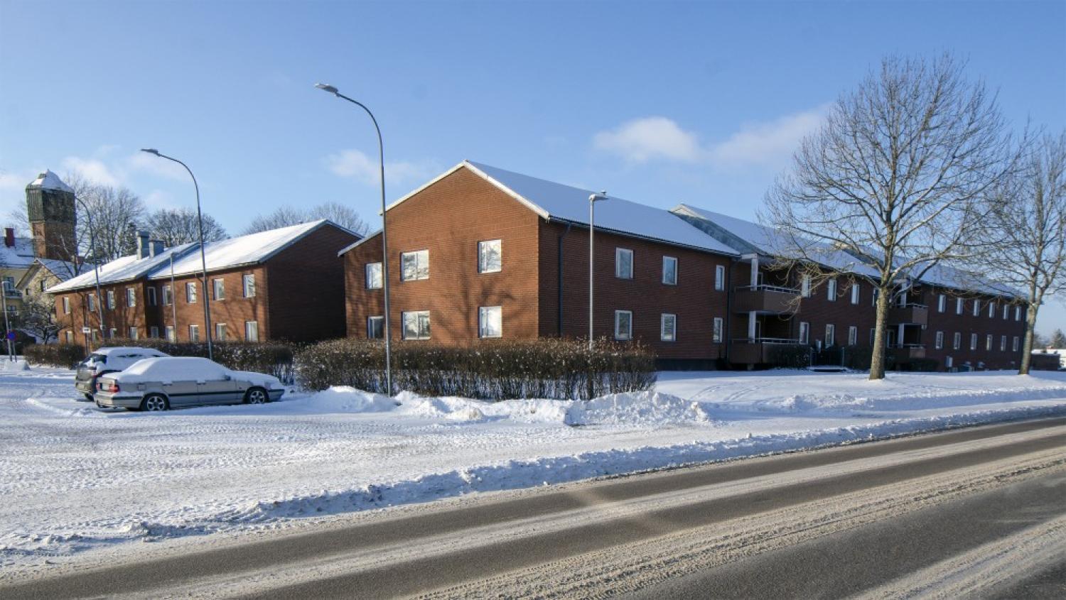 Ett hyreshus i rött tegel med snö på marken.
