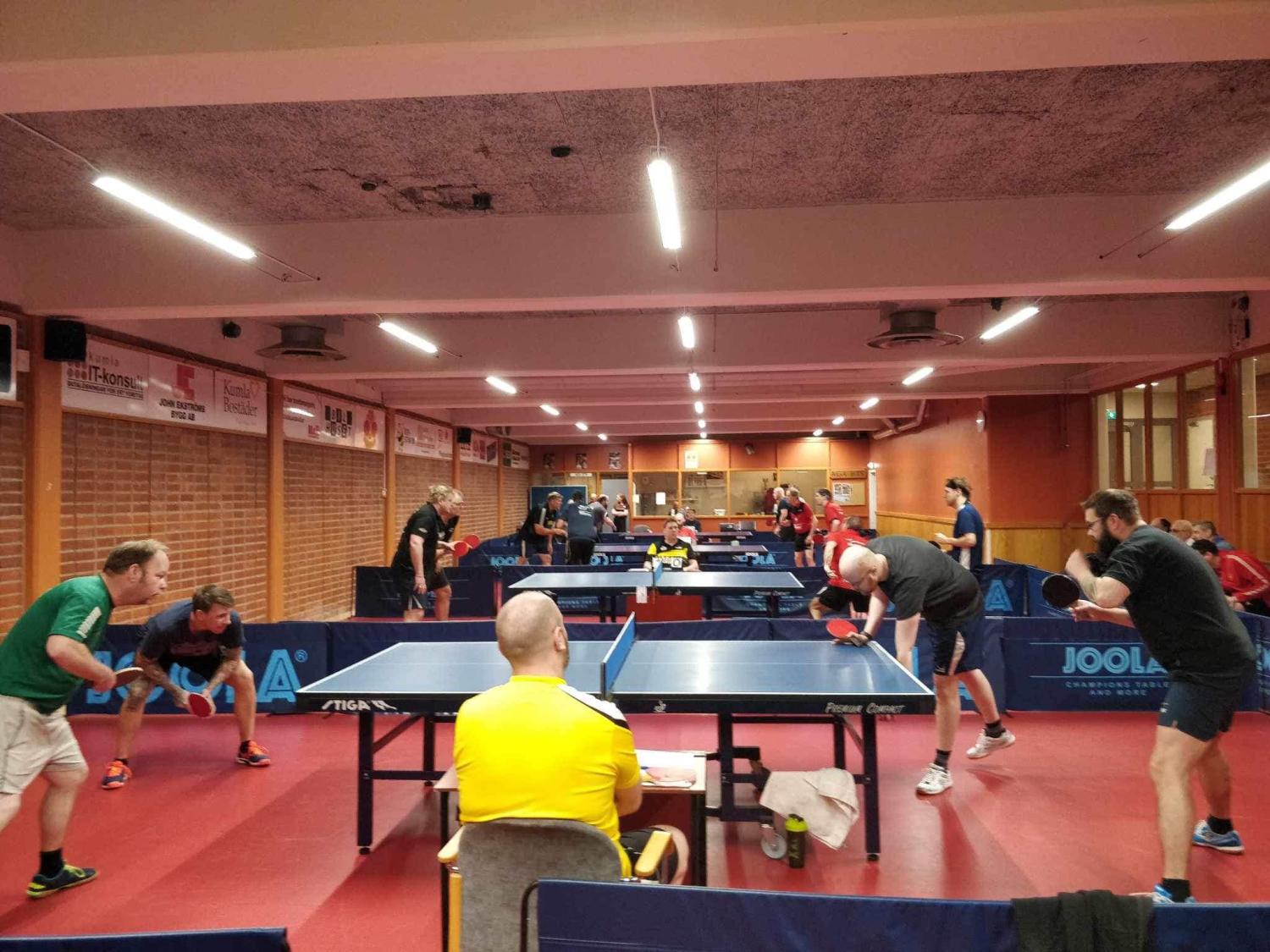 En grupp människor som spelar pingis på ett gym.