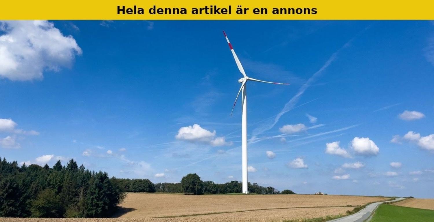 En vindkraftverk står på en åker på landsbygden under en blå himmel med spridda moln.