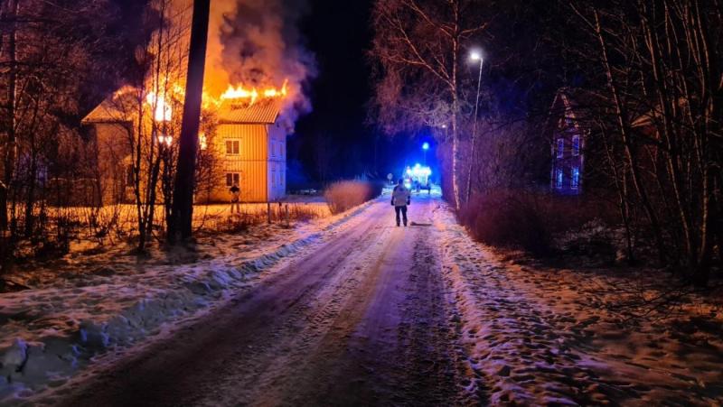En brand i ett hus på en snöig väg.