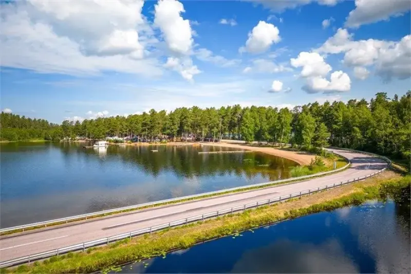 En väg omgiven av träd och en sjö.