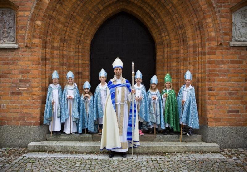 En grupp präster poserar framför en kyrka.