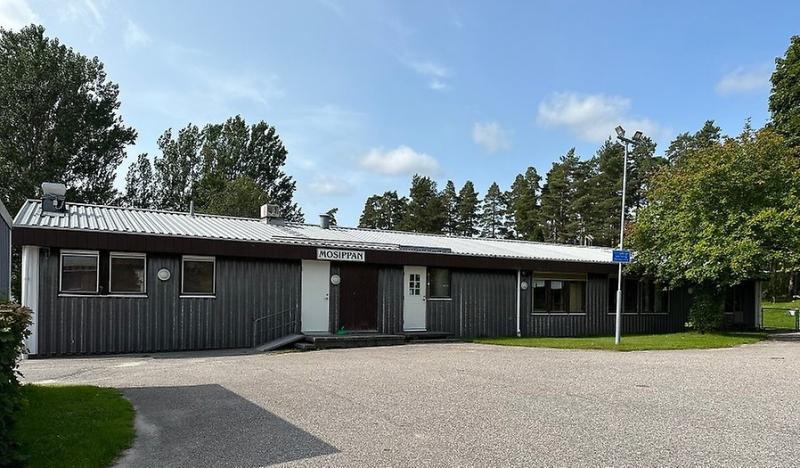 En envånings grå träbyggnad med en skylt med texten 