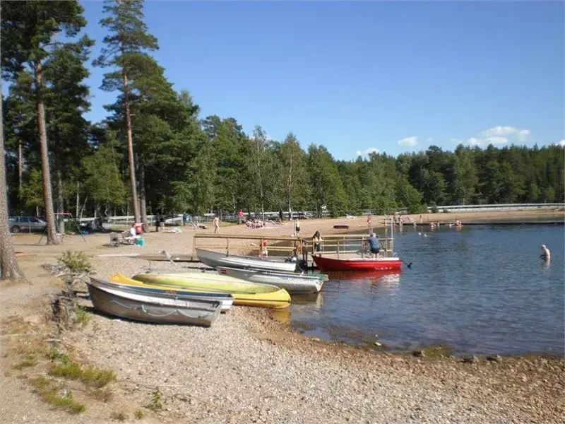 En grupp båtar ligger vid stranden av en sjö.