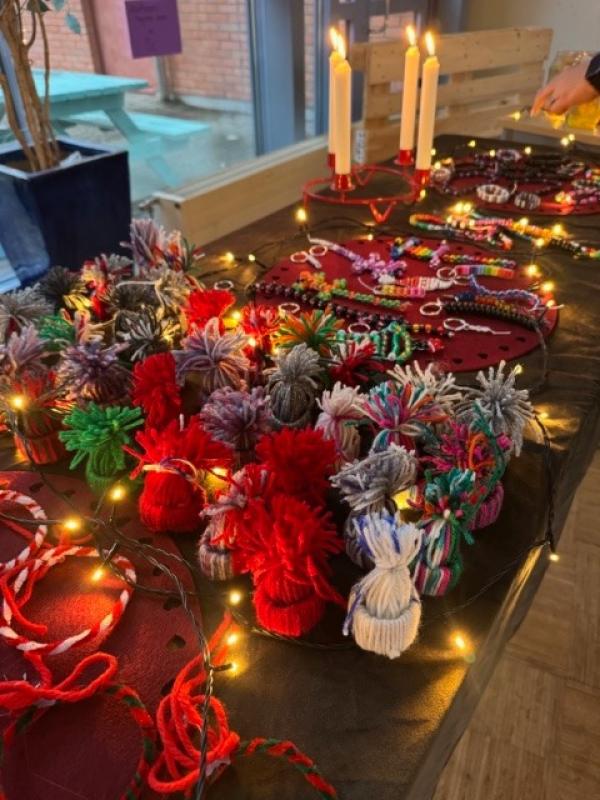 En uppvisning av färgglada garnpom-poms och pärlprydnader på ett bord dekorerat med ljusslingor och tända ljus.