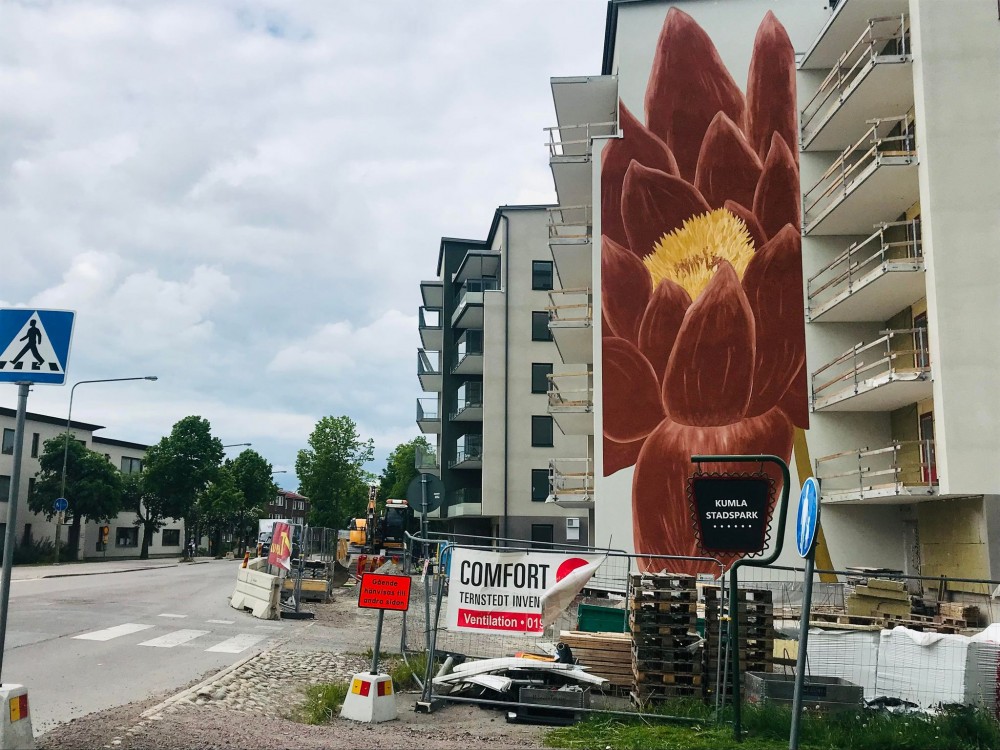 En röd blomma tornar upp sig på fasaden vid de nya husen nära Kumlasjön. Foto: Anders Björk