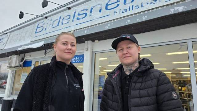 Två personer står framför en butik med en skylt med texten 