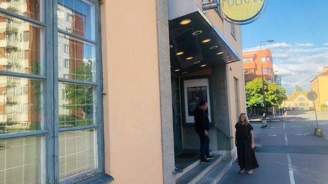 En man och en kvinna står utanför entrén till en byggnad med en 