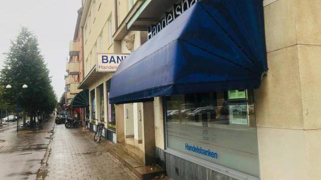 En trottoar en regnig dag intill en byggnad med blå och gröna markiser med skyltar som visar 