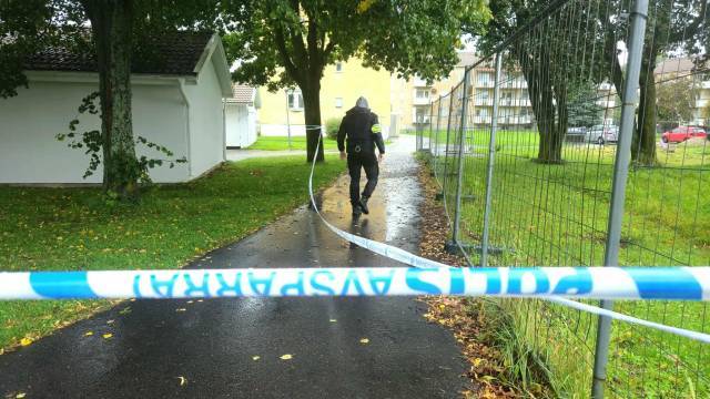 En polisman går längs en stig bakom blå och vita 