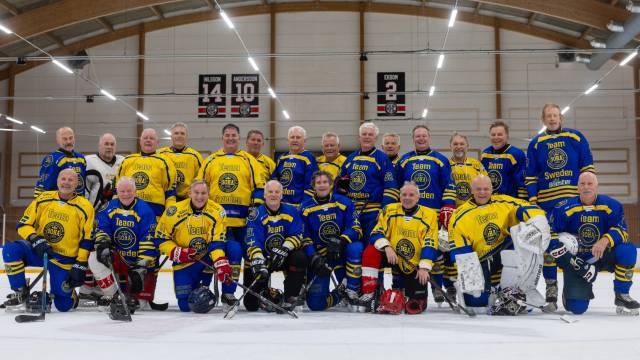 En grupp män i blågula hockeyuniformer poserar tillsammans på en inomhusisbana.