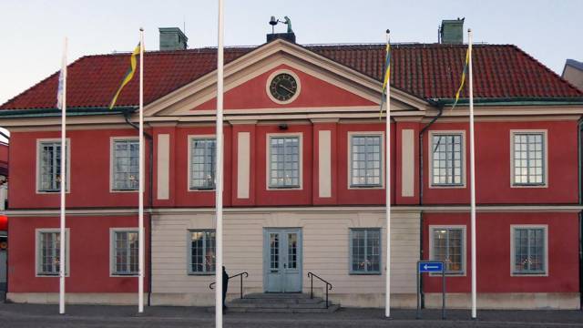 En röd byggnad med flaggor som vajar framför sig.