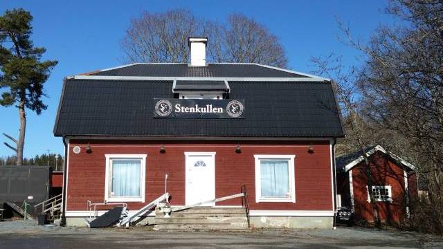 En röd träbyggnad med svart tak, märkt 