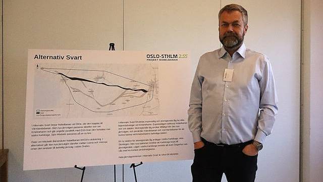 En man står bredvid en presentationstavla med en karta och en text med titeln 