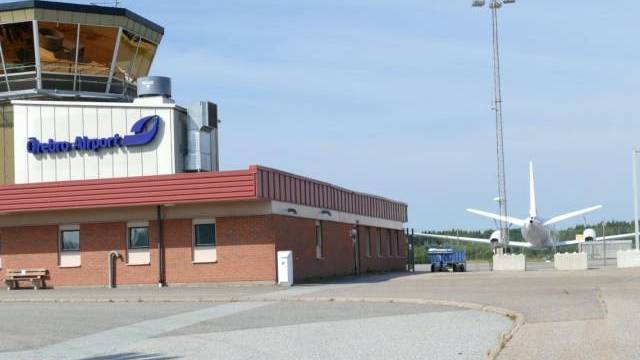 Ett plan står parkerat framför ett flygplatskontrolltorn.