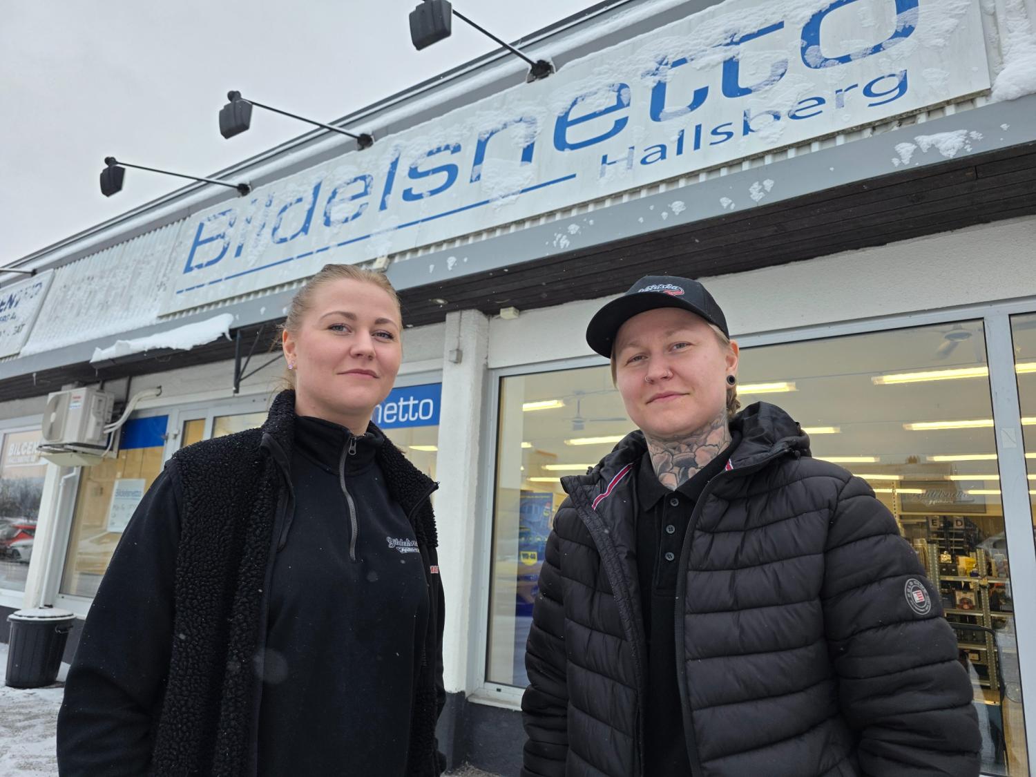 Två personer står framför en butik med en skylt med texten 