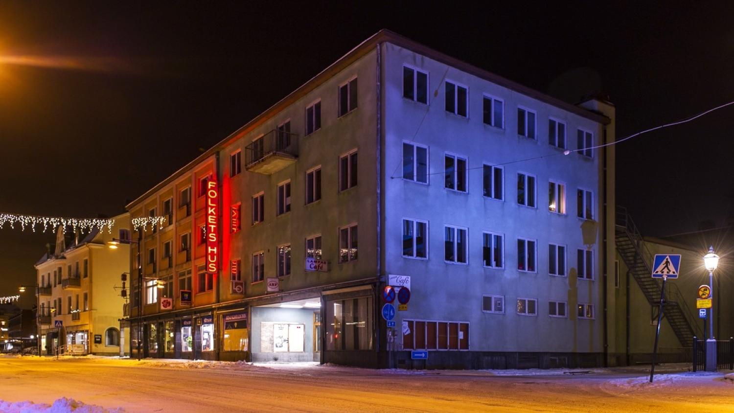En stor byggnad med en röd neonskylt med texten 