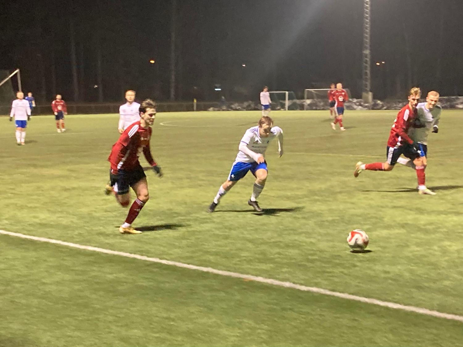 En grupp män som spelar fotboll på en plan på natten.