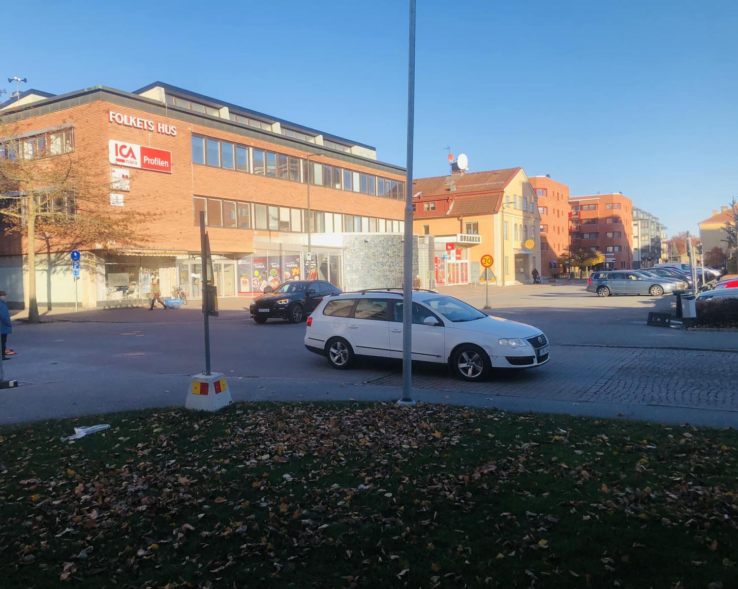 En vit bil står parkerad i ett gathörn nära en tegelbyggnad med 