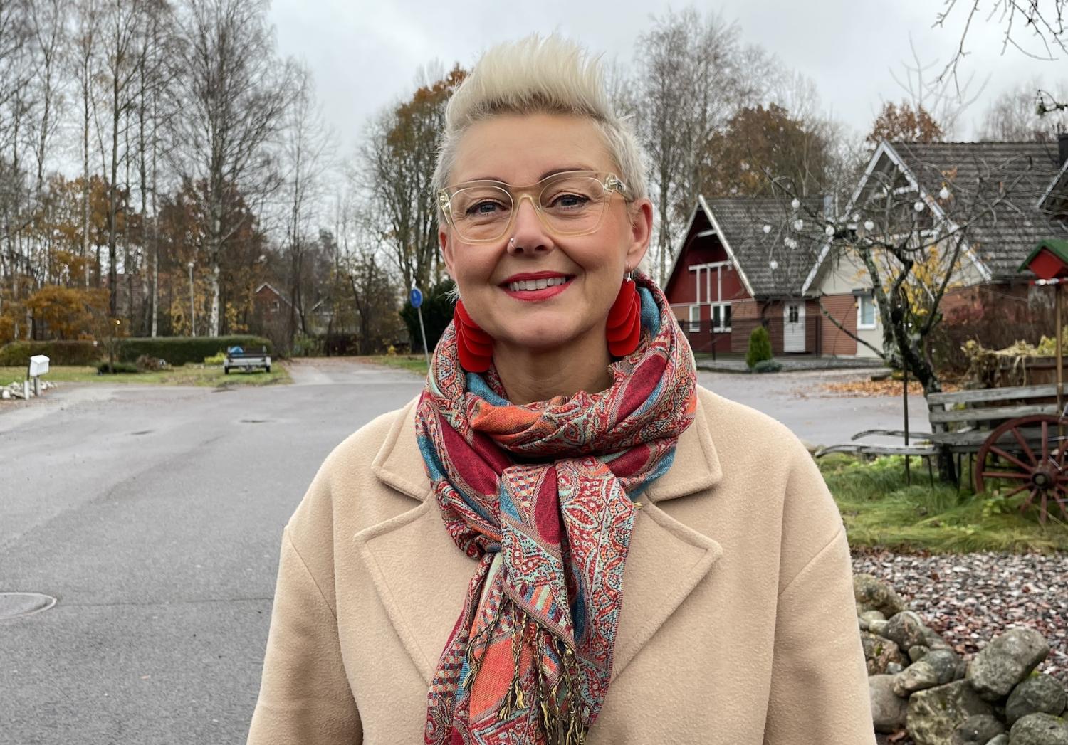 En kvinna som bär en halsduk framför ett hus.