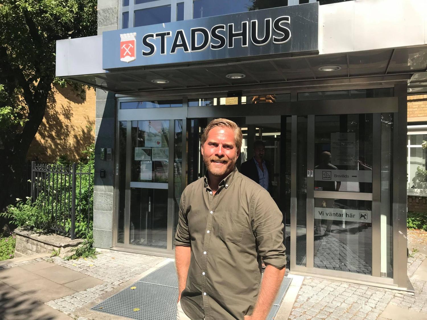 Man ler framför entrén till en byggnad märkt 