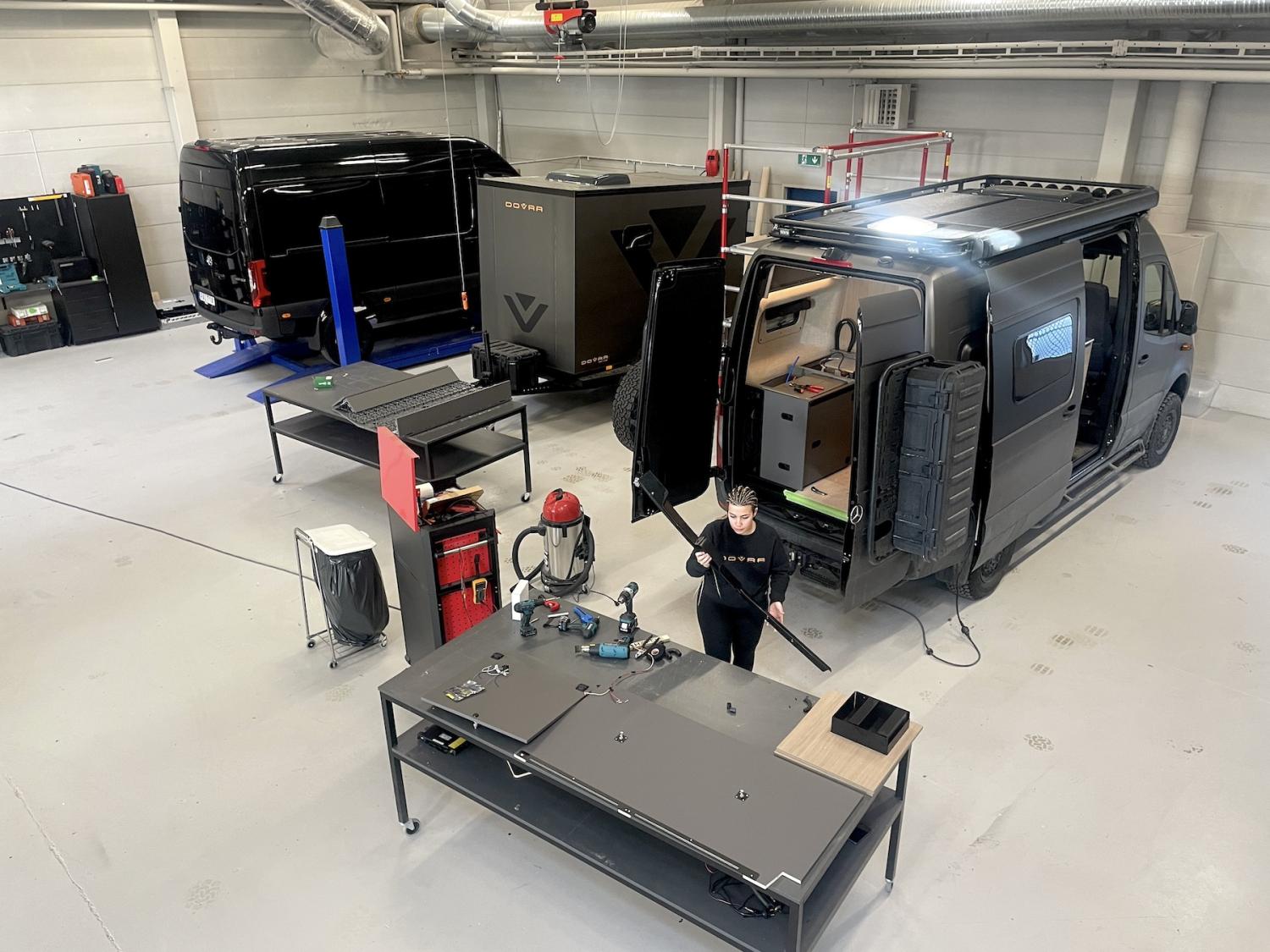 En tekniker arbetar i ett rent garage utrustat med ett fordon och olika verktyg och arbetsstationer.