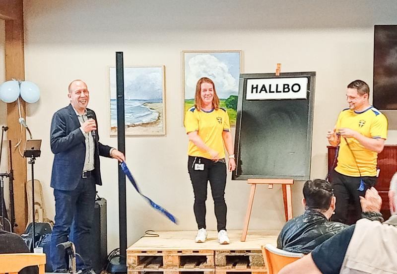 Tre personer står nära en tavla med texten 