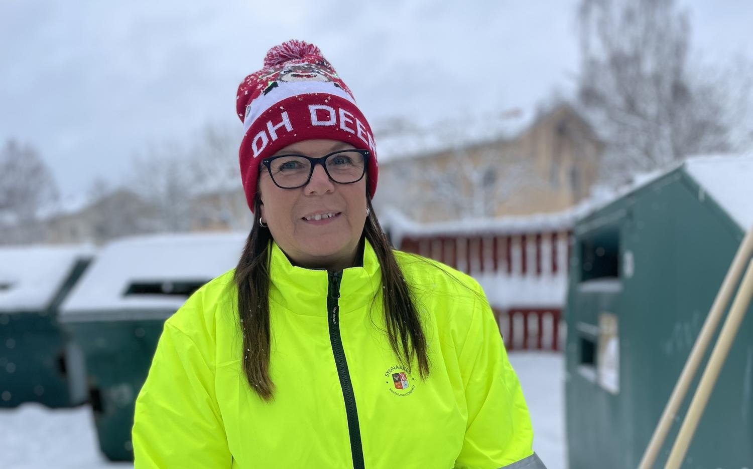 En kvinna i en gul jacka som står i snön.