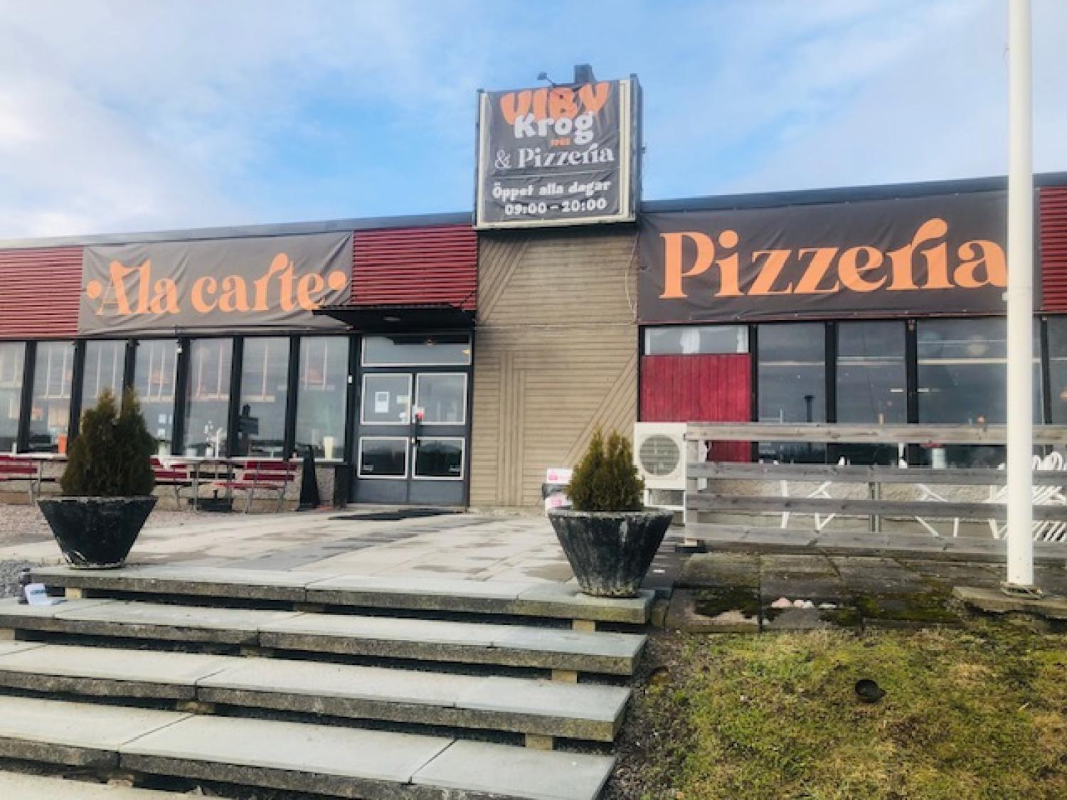 Entrén till en restaurang som heter Viby Krog & Pizzeria, med uteservering och skyltar med texten 