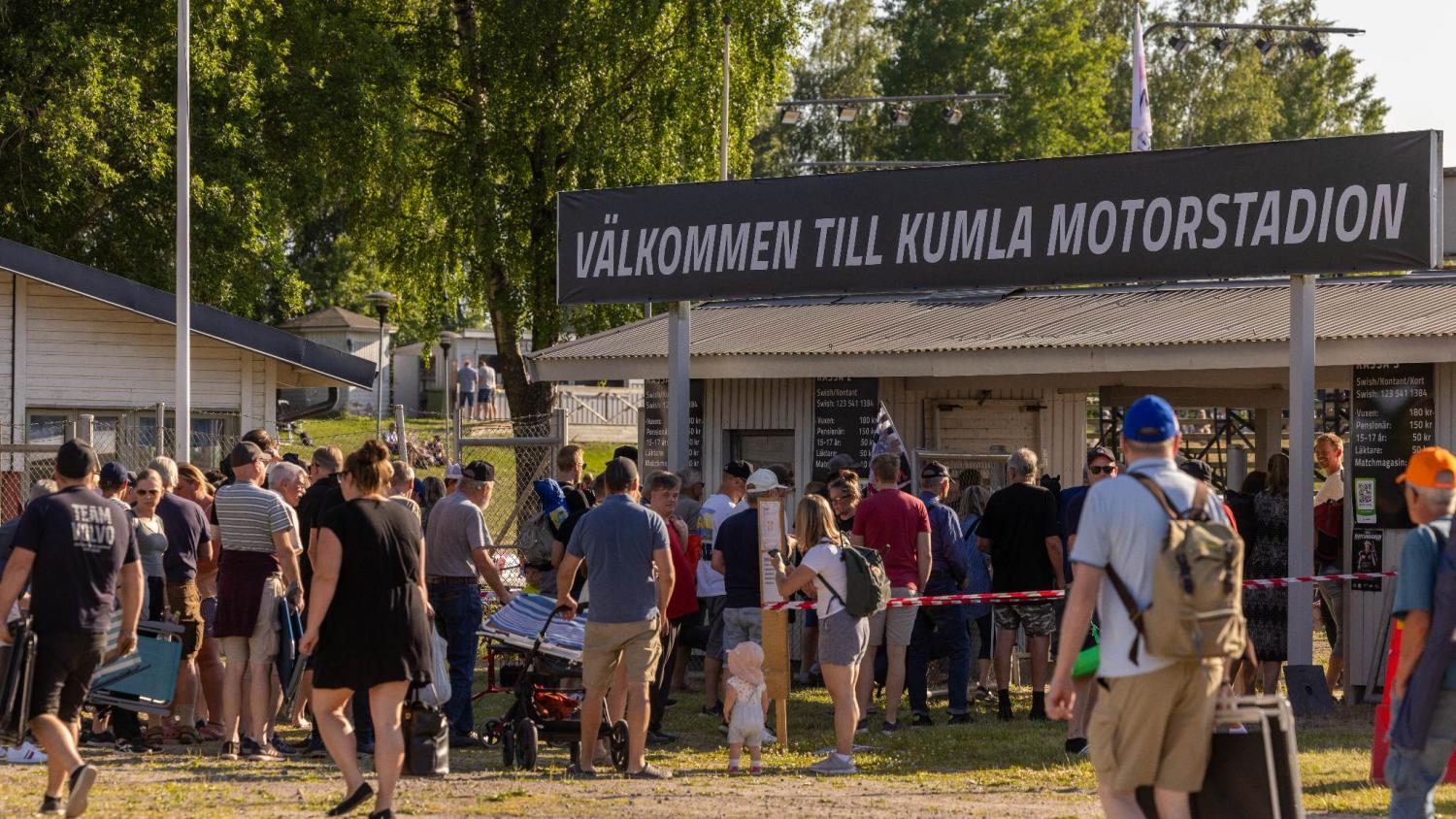 En folkmassa går in på Kumla Motorstadion under en stor skylt med texten 