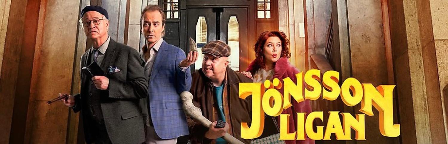 Fyra personer i färgglada kläder står framför utsmyckade dörrar; den gula texten 