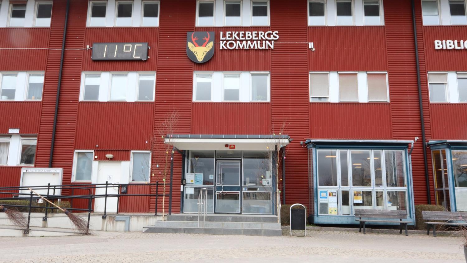Entrén till Lekebergs Kommun med en digital display som visar 11°C; röd fasad, glasdörrar och fönster syns.