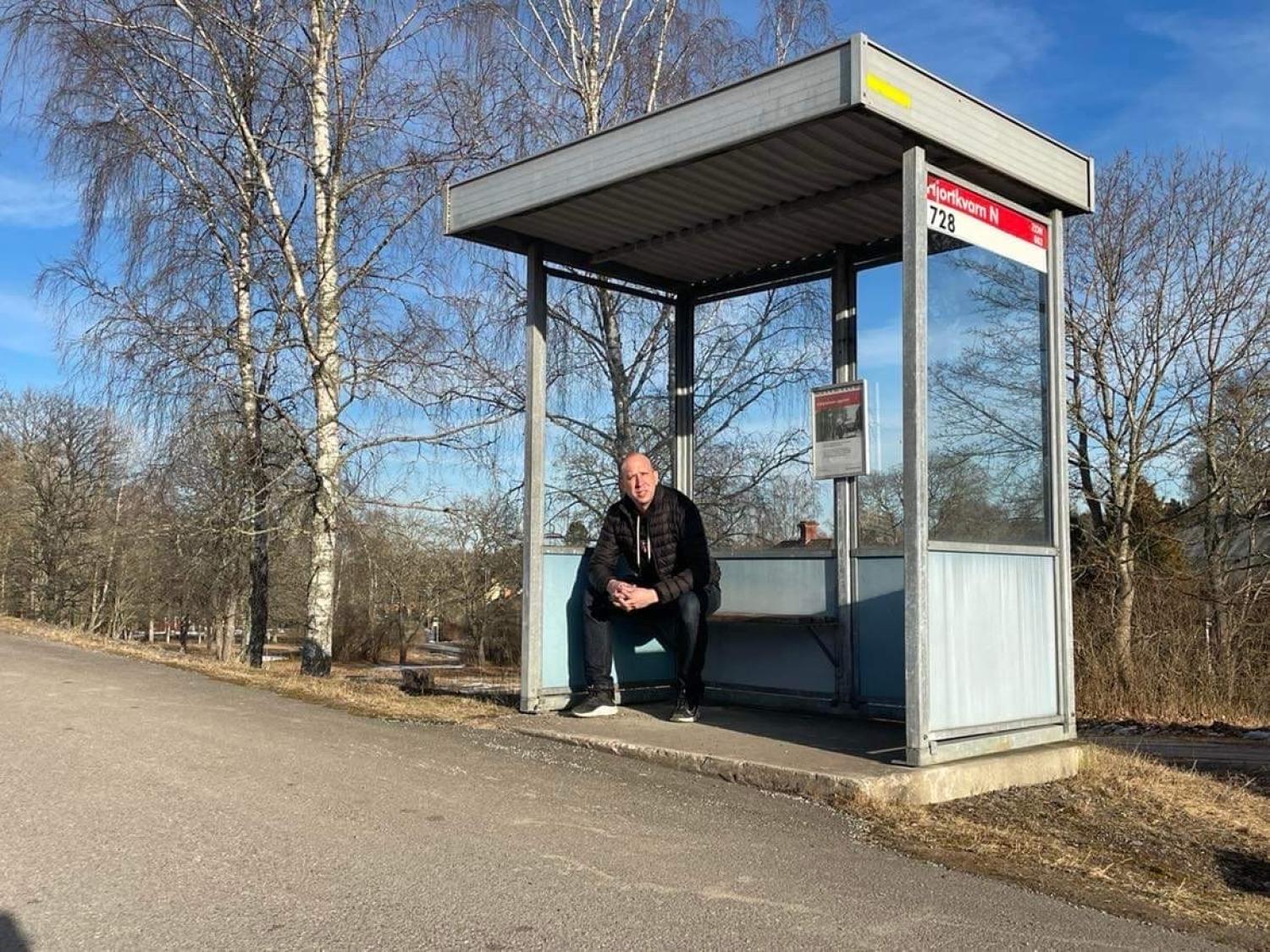 En man som sitter framför en busshållplats.
