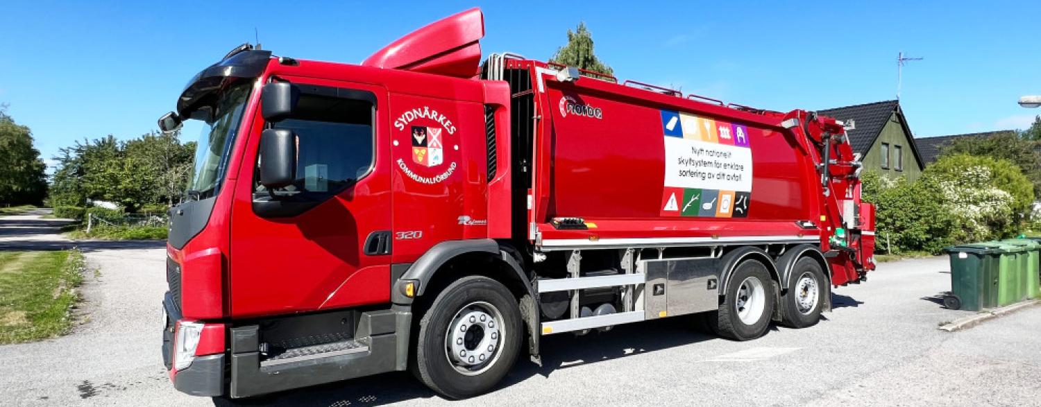 En röd sopbil parkerad på en gata.