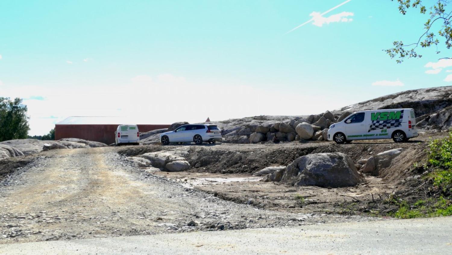 Två skåpbilar parkerade på en grusväg bredvid stenar.