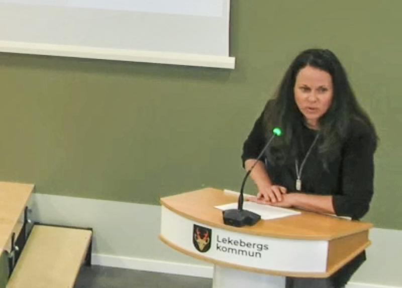 En kvinna står vid ett podium märkt 