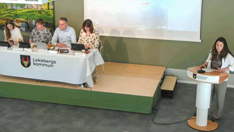 En kvinna talar vid ett podium märkt 