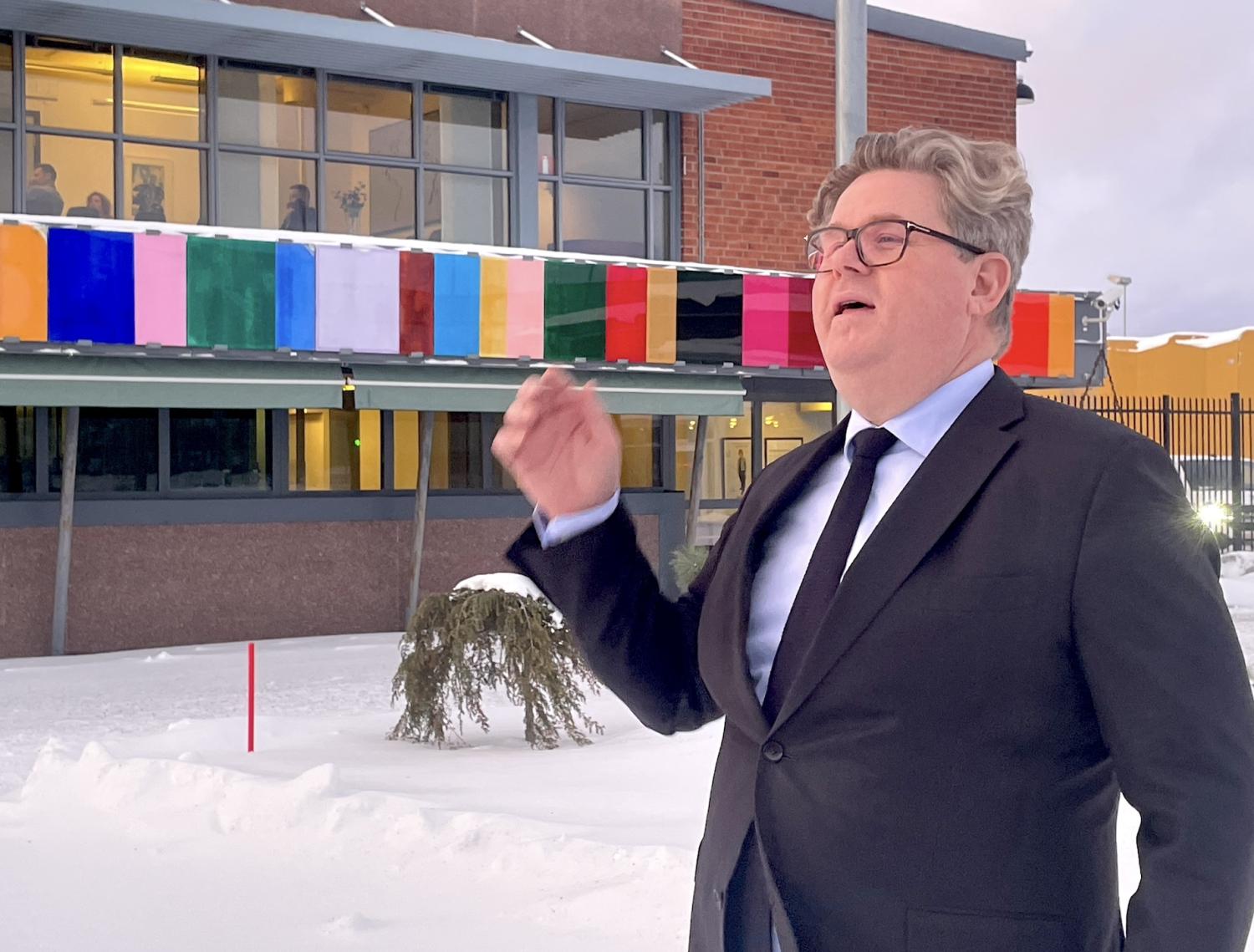 En man i kostym som står framför en byggnad.