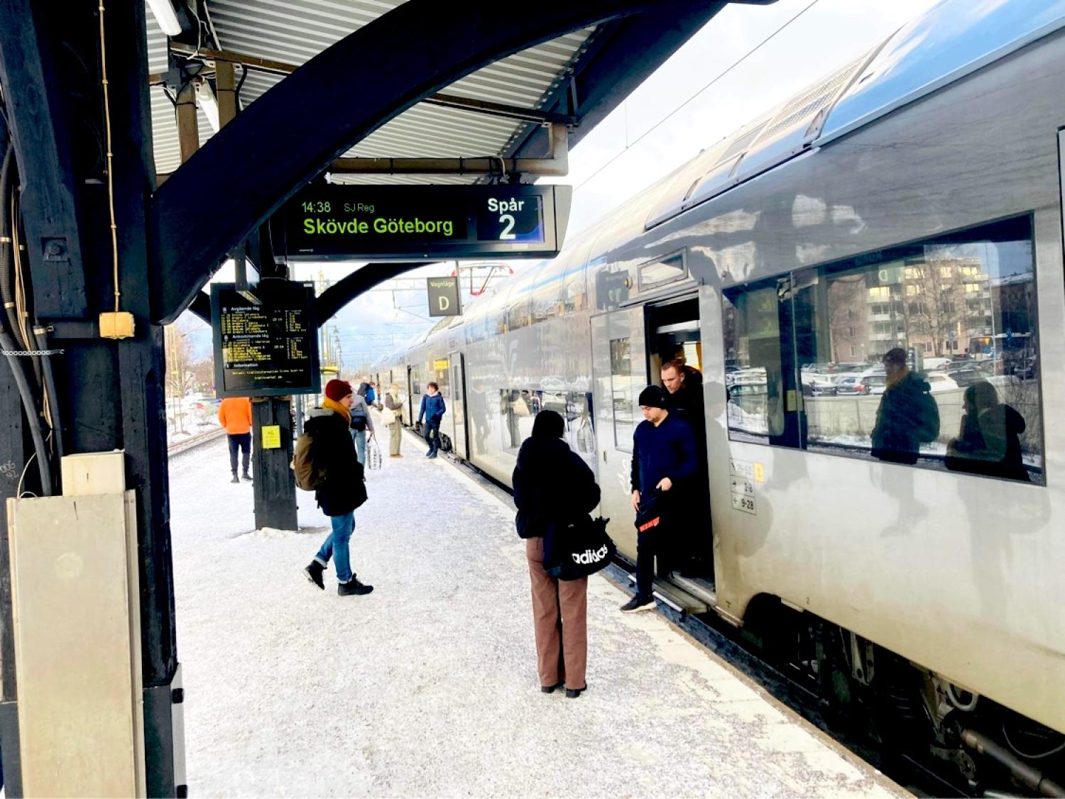 Människor som går ombord på ett tåg på en station med snö på marken.