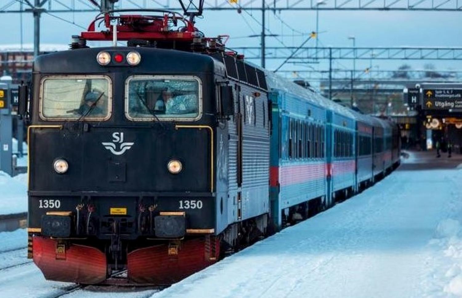 Ett svart tåg färdas längs spåren i snön.