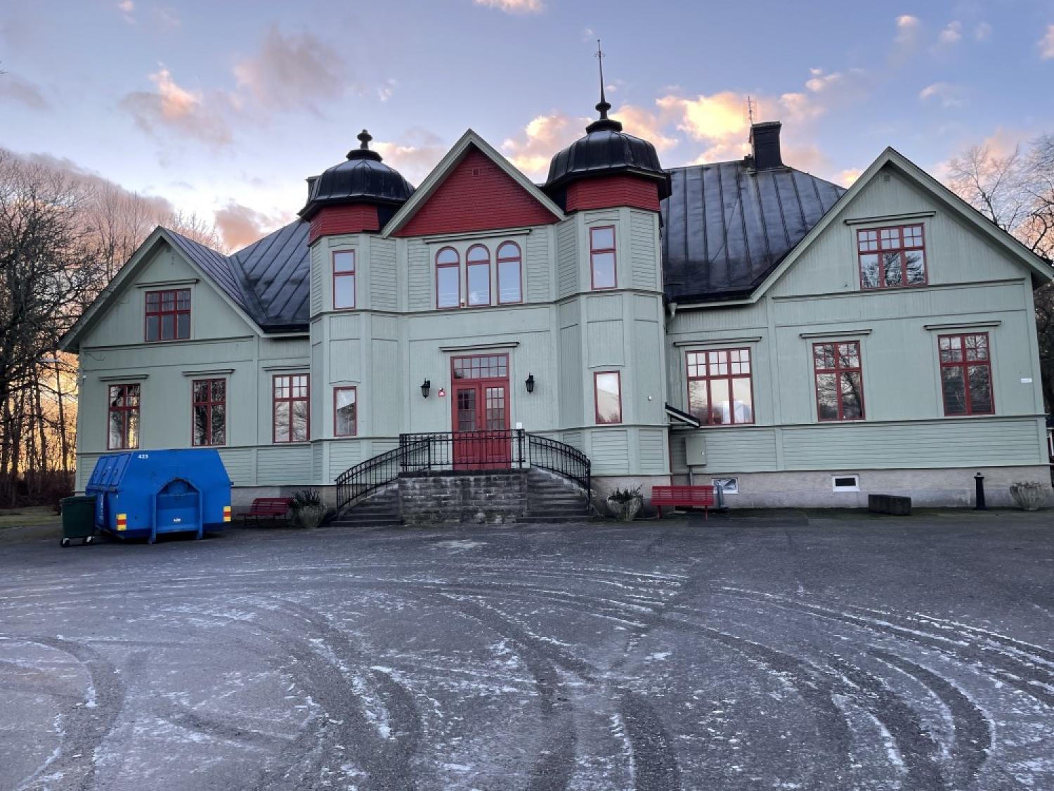 Ett rött och grönt hus med snö på marken.